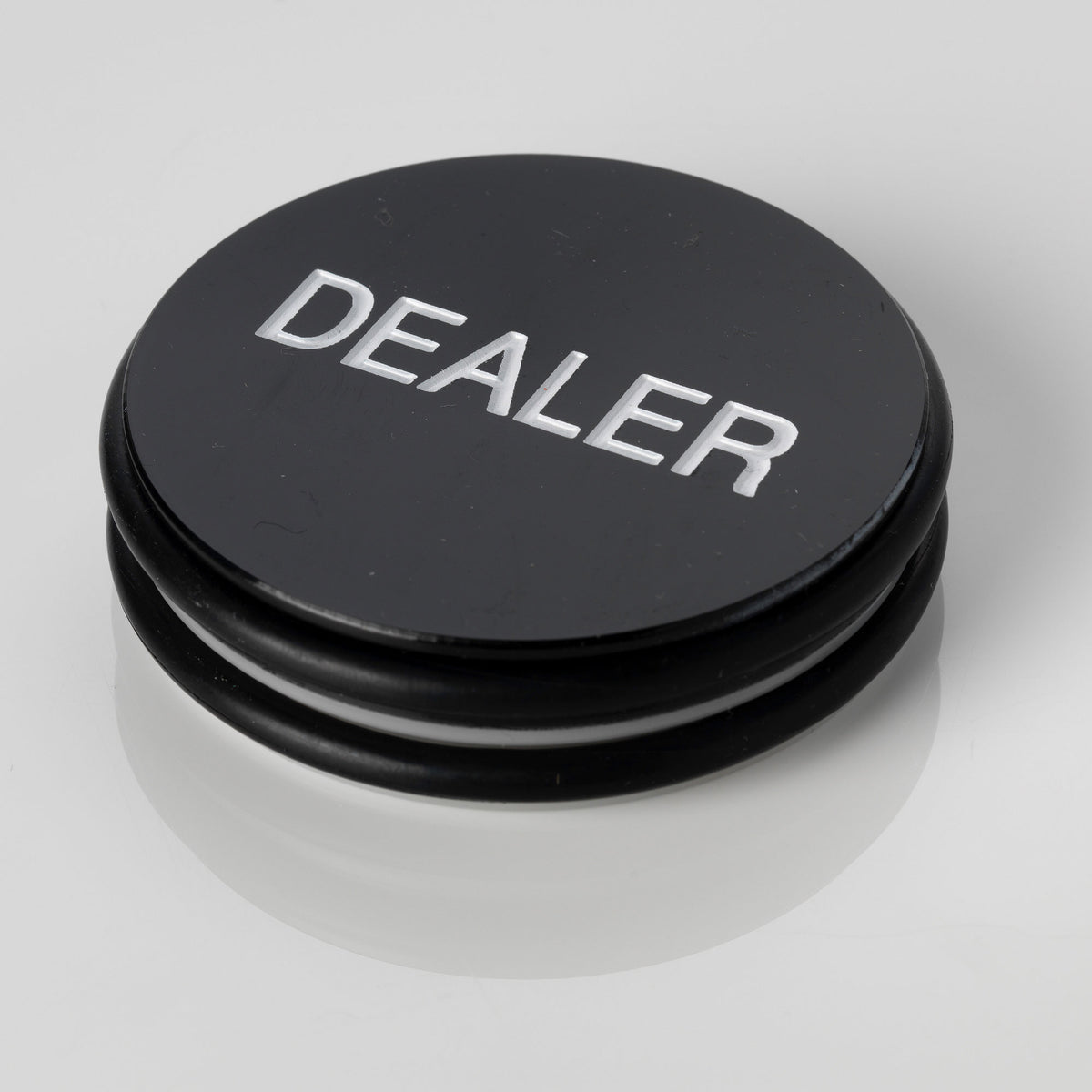 Large black 3 inch poker dealer button with DEALER embossed in white lettering