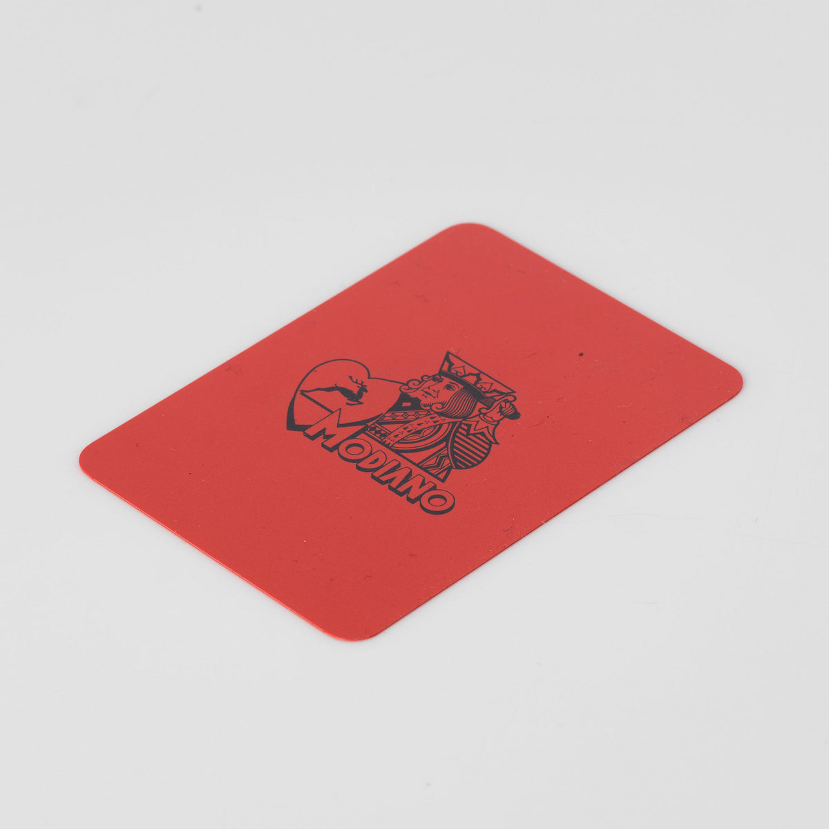 Red plastic Modiano card cut for poker and blackjack dealing, with a printed black logo