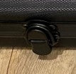 Close-up of the black latch on an ABS poker chip case resting on a wooden surface