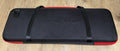 Closed black EVA poker chip case with red trim and two carry straps, seen from above