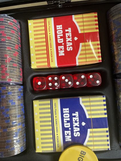 Red and blue Texas Hold'em card decks with red dice inside the poker case beside poker chips