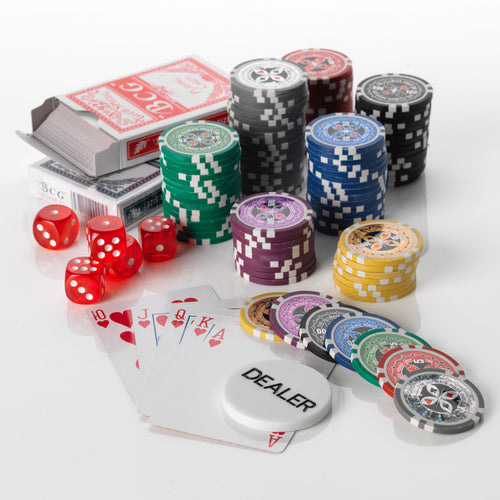 Ultimate poker set with stacks of coloured chips, red dice, card decks and a dealer button on a white background
